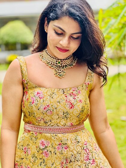 A close-up of the floral brocade gown, showing the texture of the fabric and the custom-embroidered waist belt.