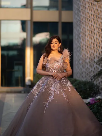 A full-length shot of our rose gold organza gown, showcasing its flowing skirt and unique one-shoulder design. This dress is a perfect blend of classic romance and contemporary fashion.