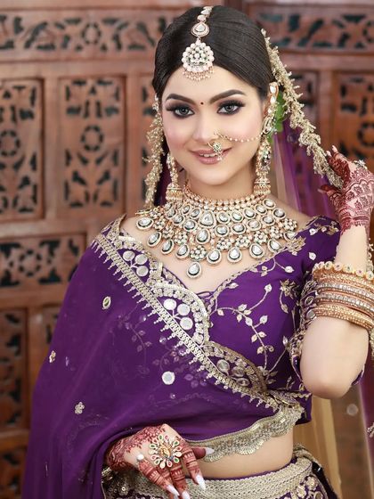A beautiful portrait of a bride in a purple lehenga. The makeup is soft and pretty, letting the color of the outfit and the jewelry shine.