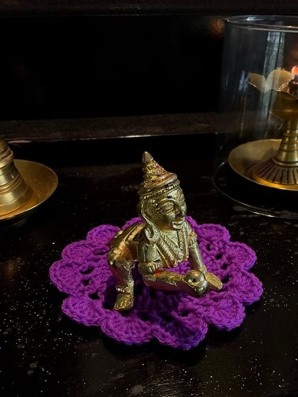 This purple flower-shaped 'asan' adds a pop of color to the puja corner.