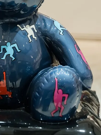A detail shot of the "Ted – Ode To Keith Haring" sculpture, showing the colorful figures dancing across the arm and leg.