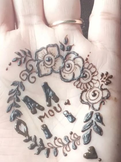 A floral wreath design incorporating the initials 'M' and 'A' on the palm.