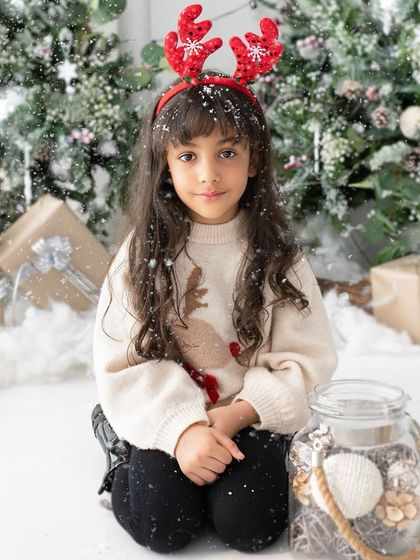 A sweet and gentle portrait with reindeer antlers and a sprinkle of snow. Her calm expression is a beautiful contrast to the usual holiday excitement.