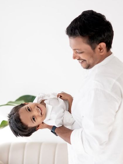 A father holding his son upside down, both laughing.
