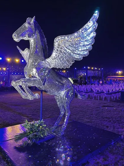 The winged Pegasus statue stands guard over the Sangeet festivities, reflecting the party lights.