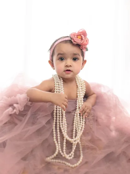 All dressed up for her first birthday. This little girl looks so elegant in her pink tulle dress and pearl necklace, a true classic portrait.