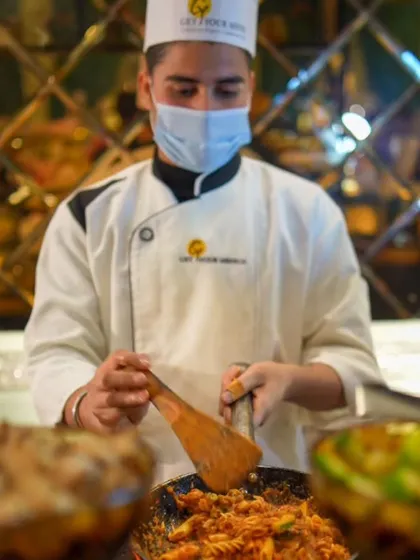 A chef at our live Italian counter, expertly tossing pasta in a pan, creating a custom dish for a guest.