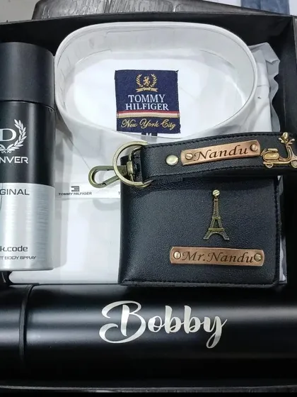 An elegant black and white themed hamper with a personalized bottle, wallet, and keychain, paired with a white shirt and deodorant.