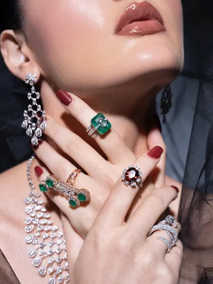 A detailed shot of the hands, adorned with beautiful emerald and ruby rings. In jewellery styling, every detail matters, from the choice of nail color to the way the hands are posed.