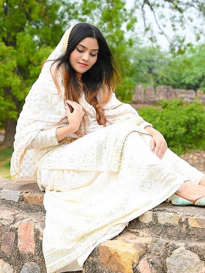 A relaxed, seated pose on a stone wall, blending traditional fashion with a natural environment.