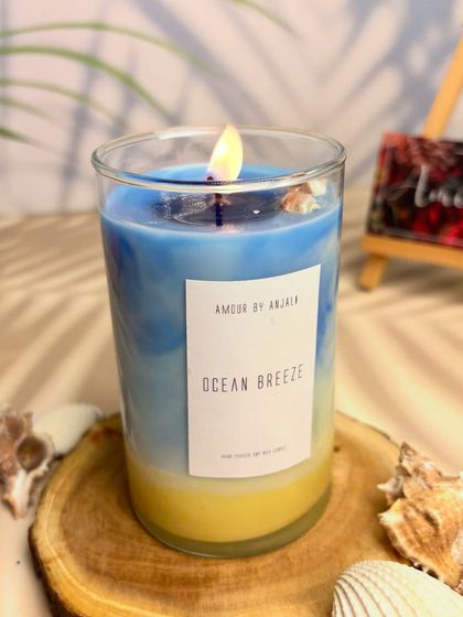 A close-up shot of the lit Beach Vibes candle, showing the beautiful layers of color and the real seashell embeds that add to its coastal charm.