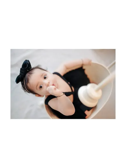 A playful look from a baby girl in a basket. I love this unique angle, which captures her curiosity and adorable expression.