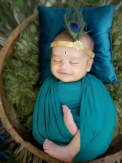 For my littlest clients, I offer unique traditional themes like this adorable Kaanha setup. This newborn photoshoot features a peacock feather headpiece and a serene, sleepy pose.