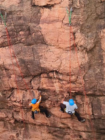 Two climbers ascend parallel routes, practicing their technique side-by-side.