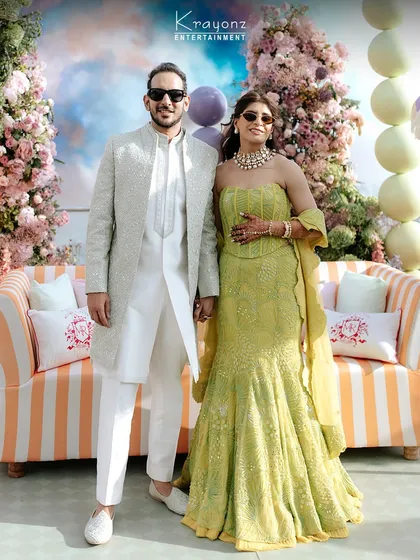 The stylish couple at their colourful Mehendi. The bride's lime green lehenga and the groom's elegant white sherwani perfectly complement the vibrant decor.