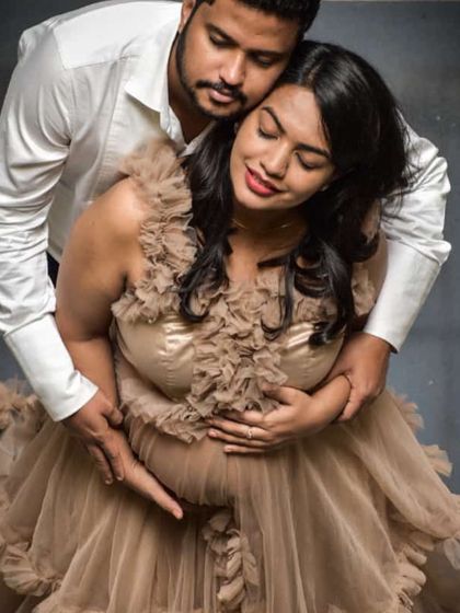 An intimate moment captured beautifully. This beige ruffled tulle gown adds a touch of soft elegance to this couple's maternity portrait, highlighting their connection.