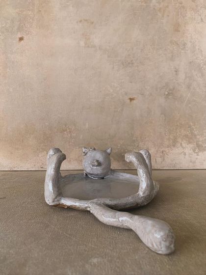 A side view of the cat-shaped dish, showing its long, elegant tail.