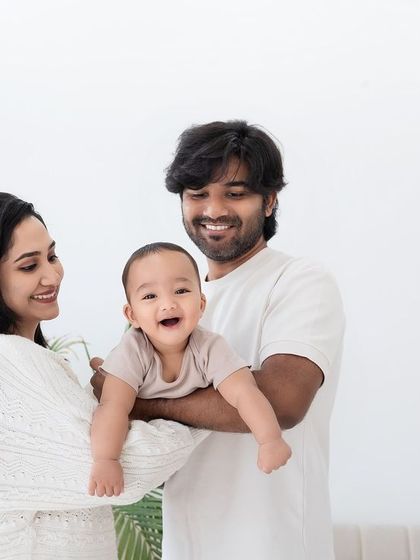 A happy family of three posing for a studio portrait.