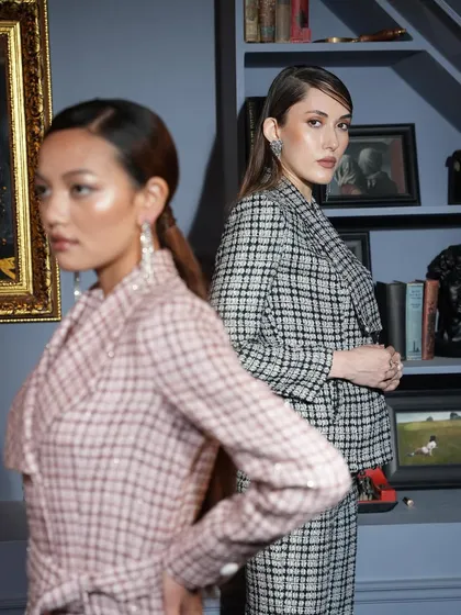 A dual-model shot with creative composition, showing one model in the foreground and another in the background. It highlights two different plaid looks from the same collection.