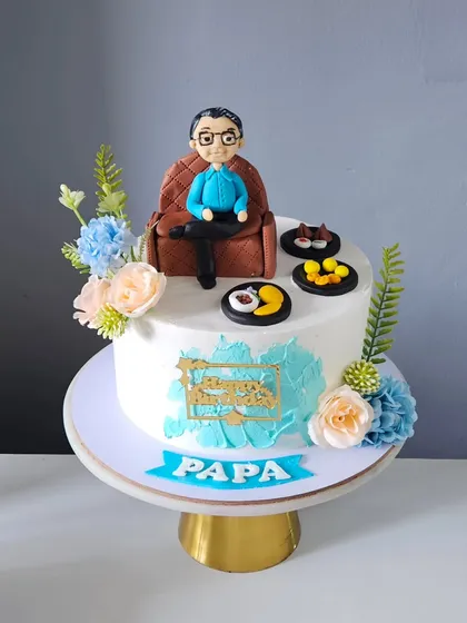 The most personal cakes are my favorite to create. For this birthday cake for a beloved father, I handcrafted an edible miniature of him in his favorite chair, surrounded by his favorite foods, making it a truly personal and heartfelt gift.