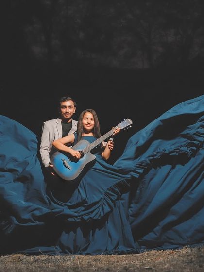 A creative and dramatic pre-wedding photo. This couple used a guitar as a prop, with the massive blue trail of the gown creating a theatrical backdrop.
