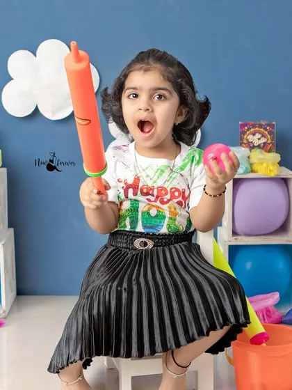 Holding a 'pichkari' (water gun), this girl is excited for the festival of colors. Her expression is priceless and full of playful energy.
