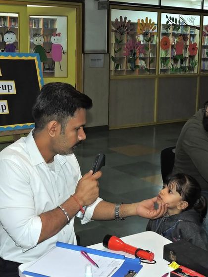 A father is present to support his child during the eye examination, showcasing our commitment to involving parents in their child's health and wellness journey.