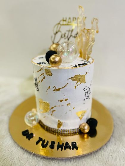 A different angle of the tall, artistic cake, highlighting the delicate gold leaf and bubble accents.