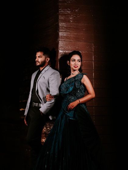 A stylish and dramatic portrait of a couple ready for their Sangeet or reception. The dark lighting and their confident poses create a powerful and modern image.