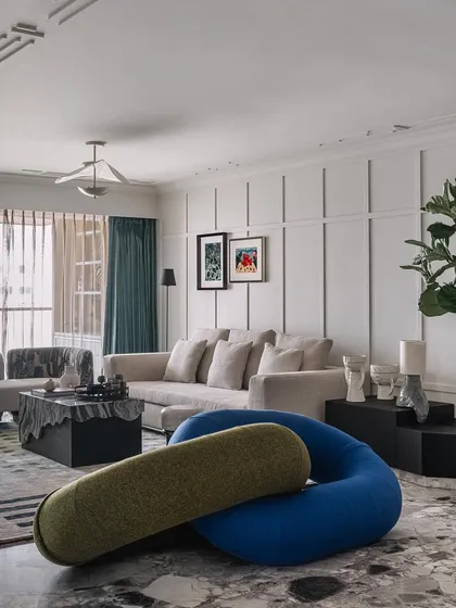 The living area of Frenchie Haus is an eclectic mix of modern furniture, textured flooring, and clean wall paneling. It's a space that feels both sophisticated and fun.