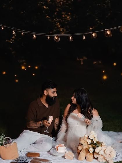 A magical evening maternity shoot with a couple sharing a toast under glowing string lights. The romantic ambiance makes for truly special and intimate photographs.