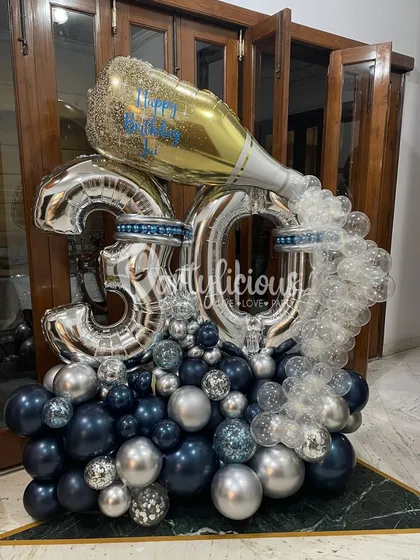 Popping the champagne for a 30th birthday! This elaborate balloon bouquet in shades of navy, silver, and glitter is the definition of celebratory. The champagne bottle foil balloon adds the perfect finishing touch.