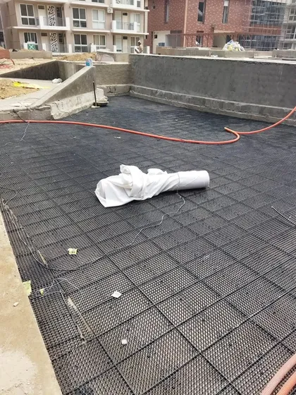 Here you can see the drainage cell system being laid out over a large area. This lightweight and strong material creates a void for water to drain, which is essential for rooftop and podium gardens.