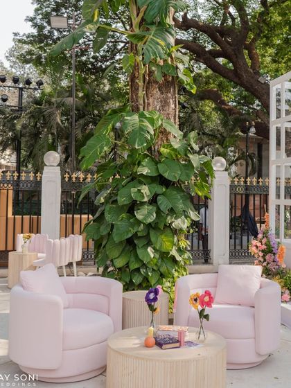 A modern pink armchair provides a pop of soft color in this outdoor lounge, surrounded by lush natural greenery.