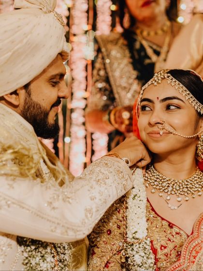 A close-up of the groom gently adjusting the bride's necklace, a small gesture of care and affection.