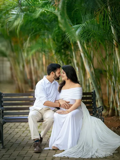 An intimate moment on a park bench. The lush palm trees in the background add a tropical feel to this romantic couple's pregnancy portrait.