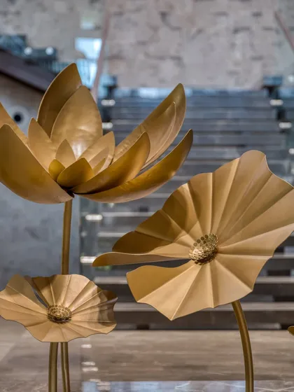 We were told you cannot grow lotuses on marble, so we did. This close-up highlights the delicate craftsmanship of our golden metal lotus sculptures. Each petal and leaf is hand-formed to create a permanent, serene garden that brings a touch of nature's elegance to a modern interior.
