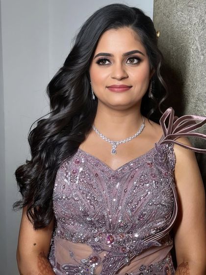 Embracing inner glamour with a super radiant base for an effortless glow. This sangeet look features shimmery purple eyeshadow and soft curls.