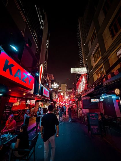 Walking through a narrow, neon-lit soi (alley) in Bangkok at night. This is where you find hidden bars and the real pulse of the city's nightlife.