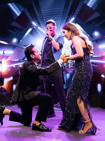 After the vows, the party begins. For this cocktail after-party, the groom serenades his bride on stage. Her midnight blue embellished gown by Shantanu & Nikhil was styled for glamour, movement, and a whole lot of fun.