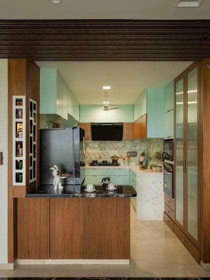 The kitchen combines wood and pastel green for a visually pleasing aesthetic, with a quartz counter and sea-green marble tiles.