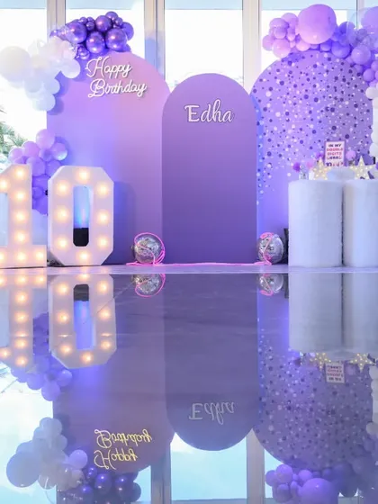 A dream in lavender for a 10th birthday party. This picture perfect setup, inspired by the movie 'Wish', features a custom backdrop with balloon art and marquee lights, all reflected for a touch of magic.