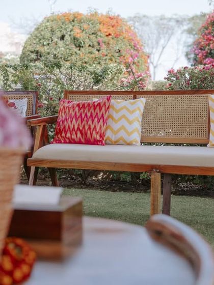 A close-up of the lounge furniture, showing the wooden frame, rattan details, and custom-printed cushions.