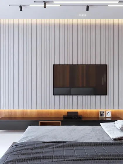 This bedroom showcases a modern TV wall unit, combining a central white fluted panel with surrounding wood-grain laminate. Backlighting enhances the textural contrast, creating a warm and inviting focal point.