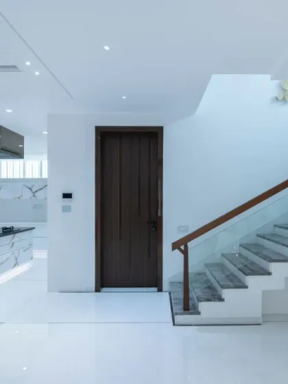 This view highlights the seamless integration of the kitchen into the open-plan living space. The all-white cabinetry and island with a striking stone pattern blend perfectly with the home's minimalist aesthetic.