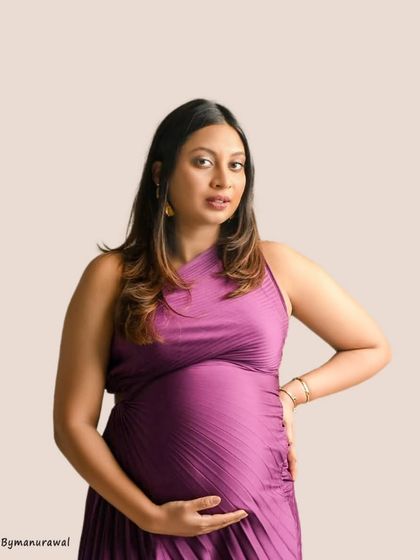 A close-up portrait in a rich purple gown, focusing on the mother's confident and serene expression. The simple background ensures that all the attention is on her and the beautiful shape of her baby bump.