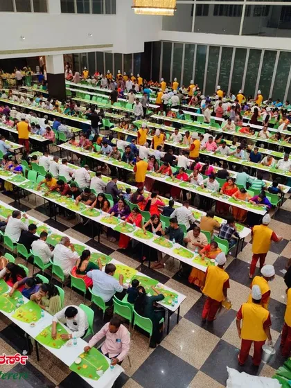 We can serve thousands of guests at once in a 'baale yele oota' (banana leaf feast) setup. This view shows our organized, large-scale service in action at a wedding reception.