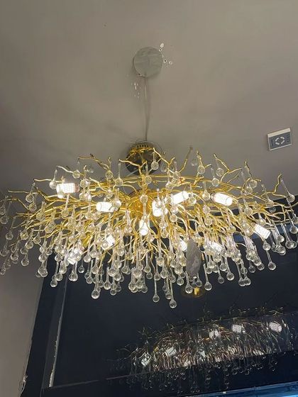 This chandelier features cascading crystal droplets on a gold frame, resembling a weeping willow. It's a dramatic and elegant choice for a high-ceiling space.