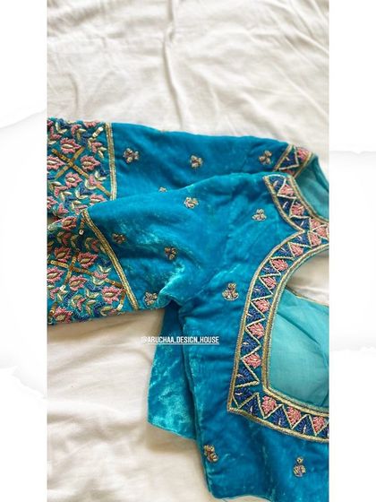 A side view of the blue velvet blouse, highlighting the intricate floral embroidery on the sleeve.