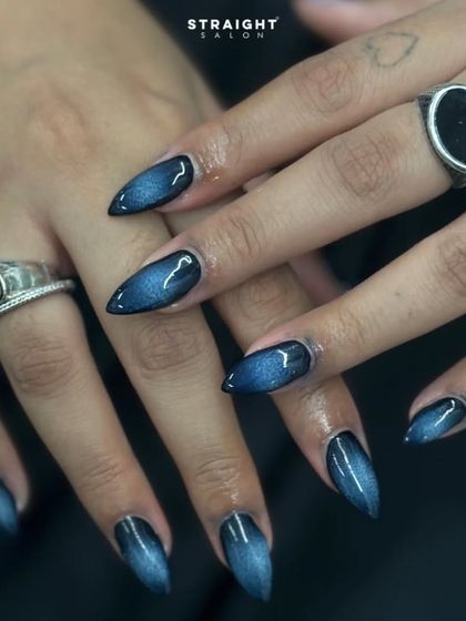 A dark and mysterious cat-eye effect on sharp stiletto nails. The blue-black magnetic polish creates a deep, velvety look that is both edgy and chic.